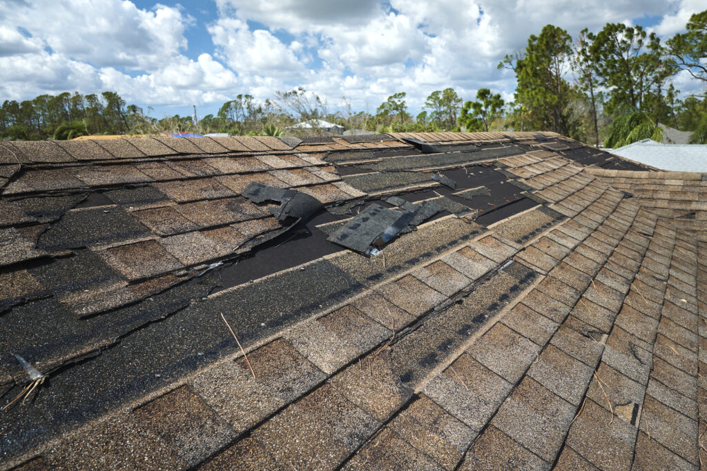 Damaged house roof with missing shingles after a storm.